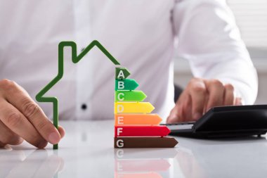 Anahat ev modeli enerji verimlilik oranı ile tutarak hesap makinesini kullanarak bir işadamı Close-up