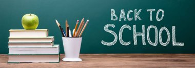 Blackboard ile okul metin geri yakınındaki yığılmış kitaplar üzerinde yeşil elma