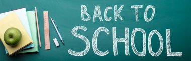 Yeşil elma, kitapları ve okul malzemeleri geri okul metin için yazı tahtası üzerinde yığılmış