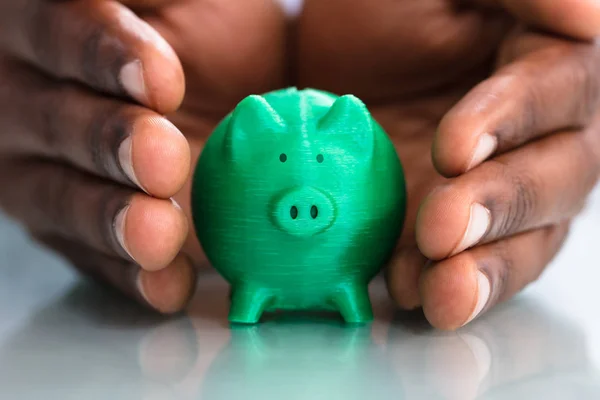 Närbild Hand Skydda Den Gröna Miniatyr Piggybank Skrivbord — Stockfoto