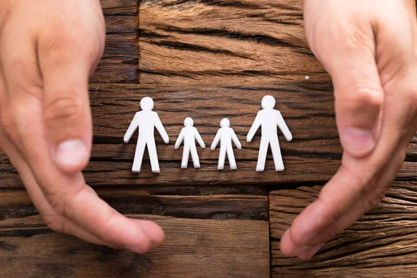 Elevated View Businessperson Hand Protecting Family Figures Wooden Background — Stock Photo, Image
