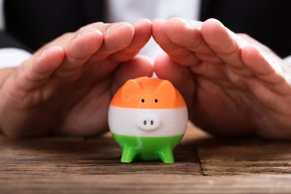 インドの旗の塗料で Piggybank を保護する実業家の手 — ストック写真