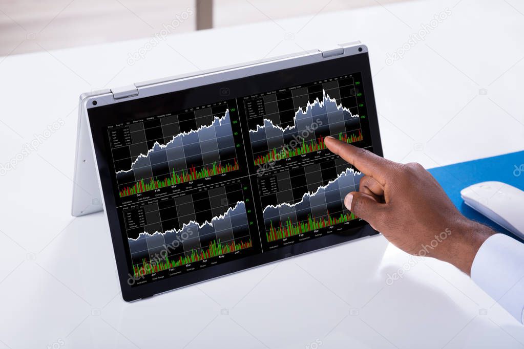 Close-up Of A Businessman Pointing On Stock Chart Over The Laptop Screen