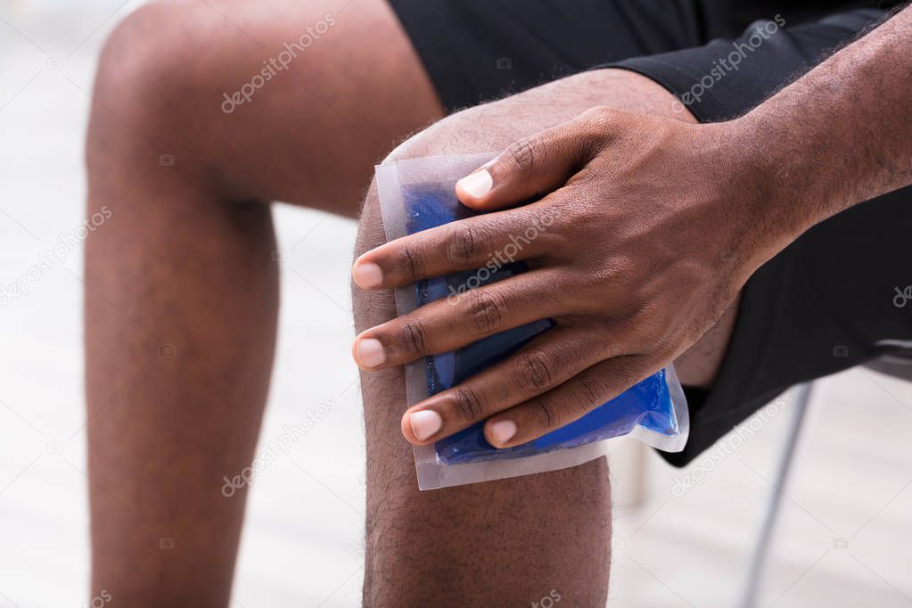Close-up Of A Man Applying Ice Gel Pack On His Knee