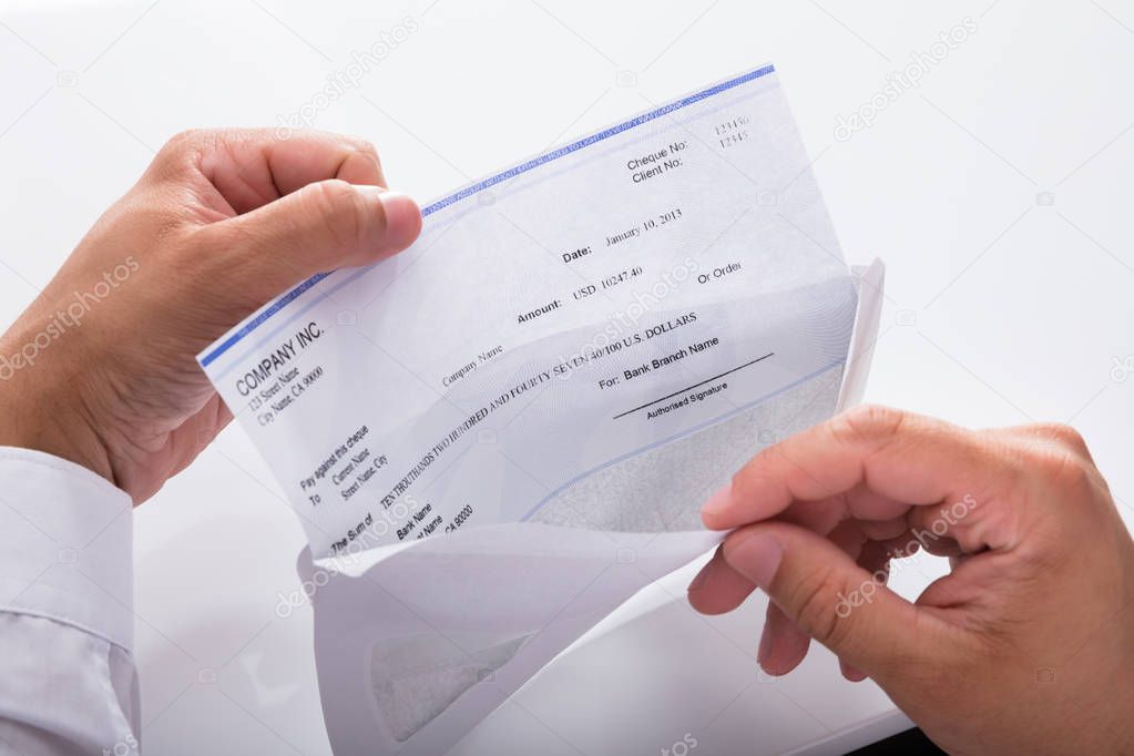 Close-up of a businessman's hand opening envelope with paycheck