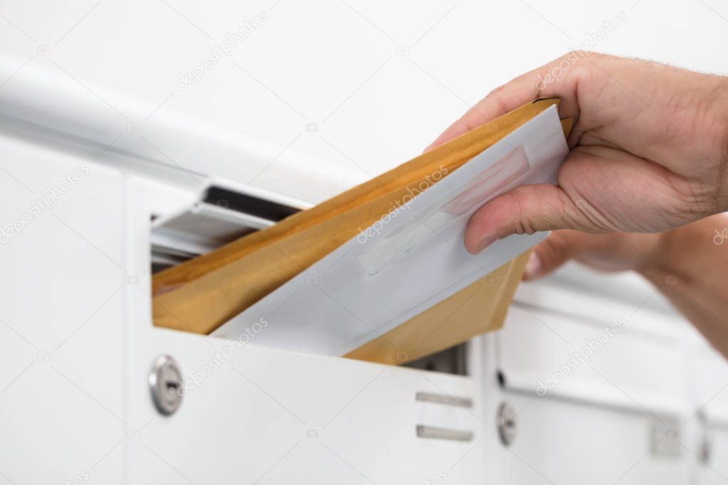 Close-up of a man's hand inserting letters in mailbox