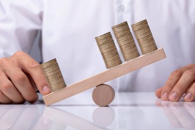 Dengesizlik ahşap tahterevalli üzerinde yığılmış jeton arasında gösterilen işadamı'nın el