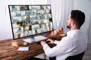 Genç işadamı CCTV kamera görüntüleri bilgisayarda ahşap Resepsiyon üzerinde izleme