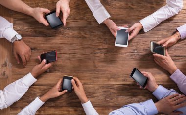 Smartphone üzerinde ahşap arka plan kullanarak iş adamları grubu