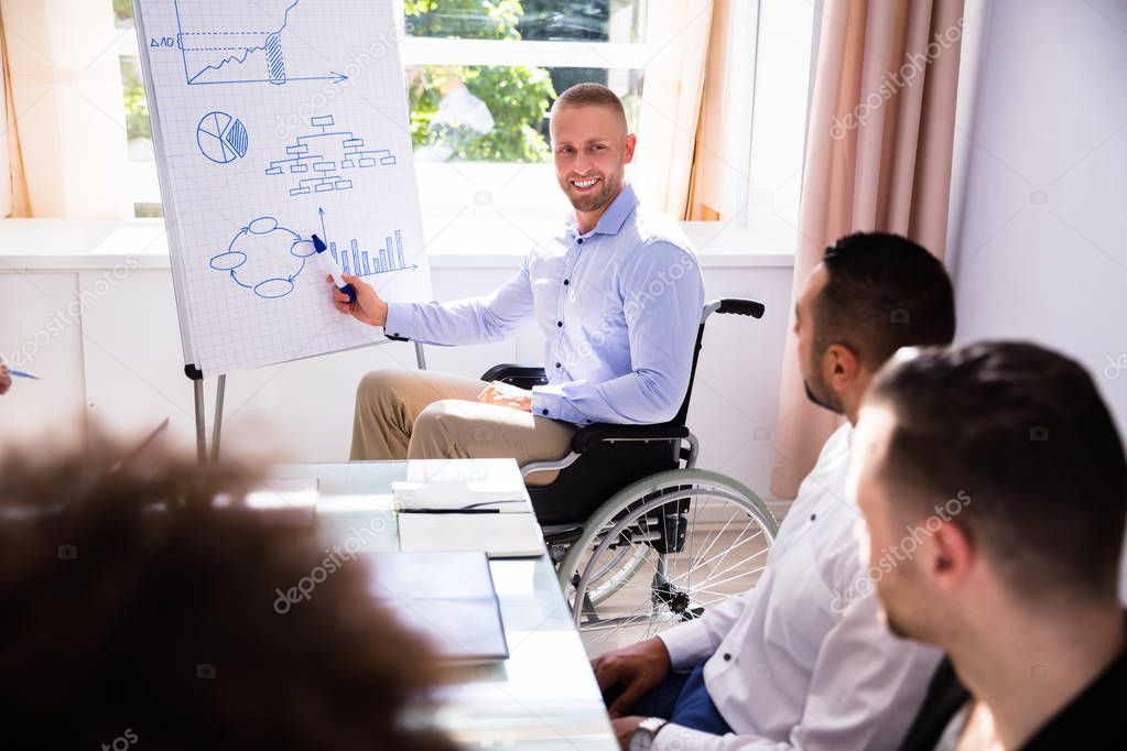 Disabled Young Businessman Giving Presentation To His Colleague