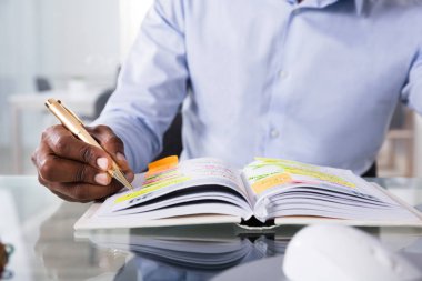 Yansıtıcı masanın üstüne kalem ile günlüğü bir işadamı yazma zamanlamada Close-up