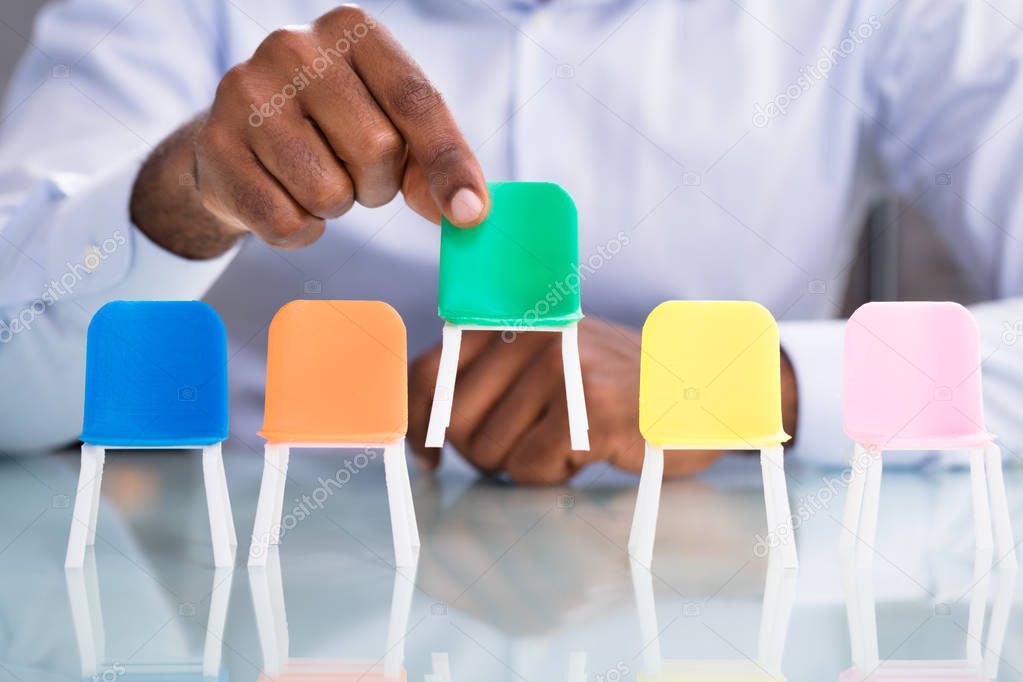 Businessman Holding Green Seat From The Colorful Chairs