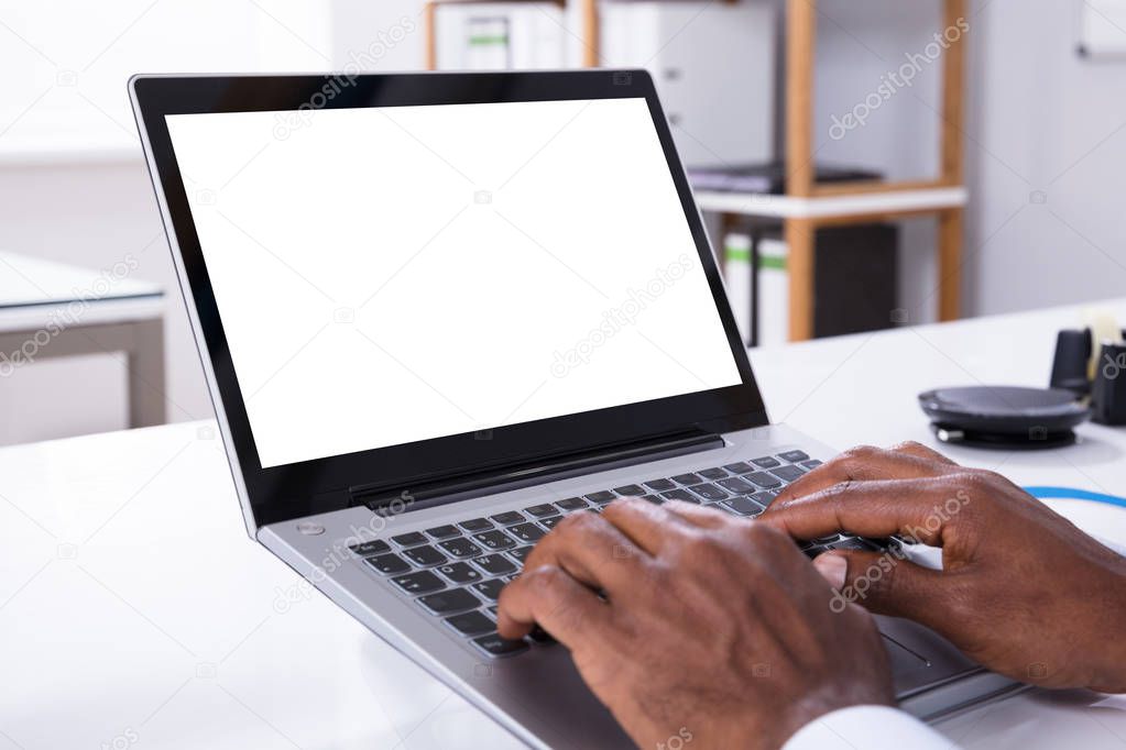 Close-up Of Man's Hand Typing On Laptop Over The White Desk