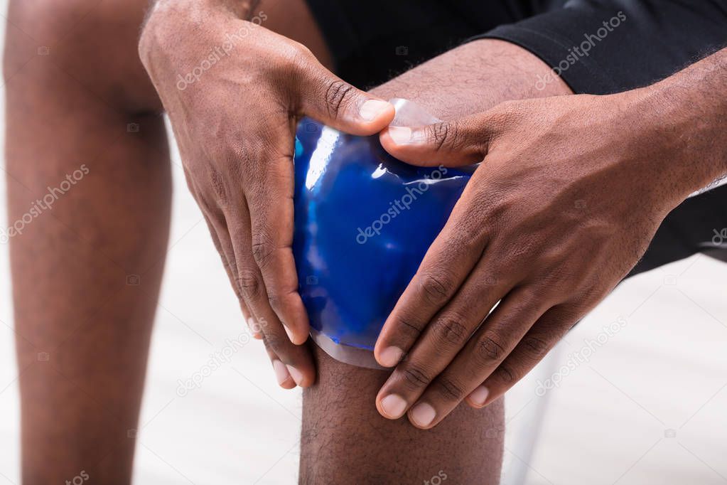 Close-up Of A Man Applying Ice Gel Pack On His Knee