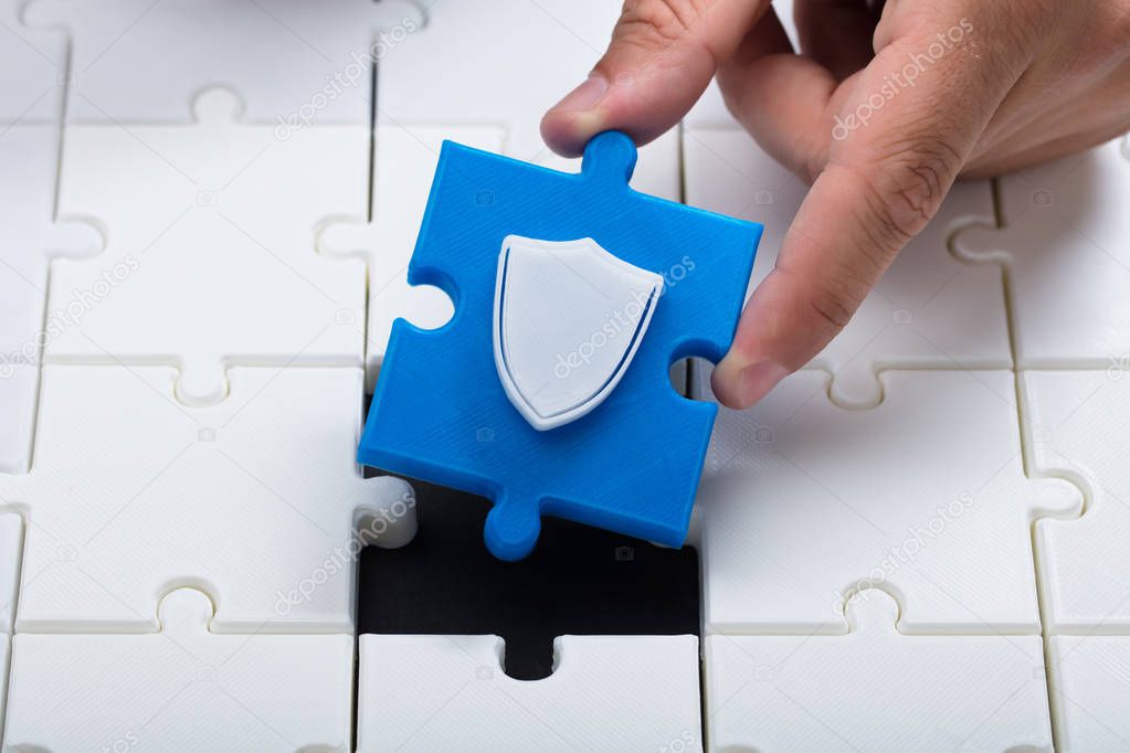 A person connecting last blue piece with shield icon into jigsaw puzzles