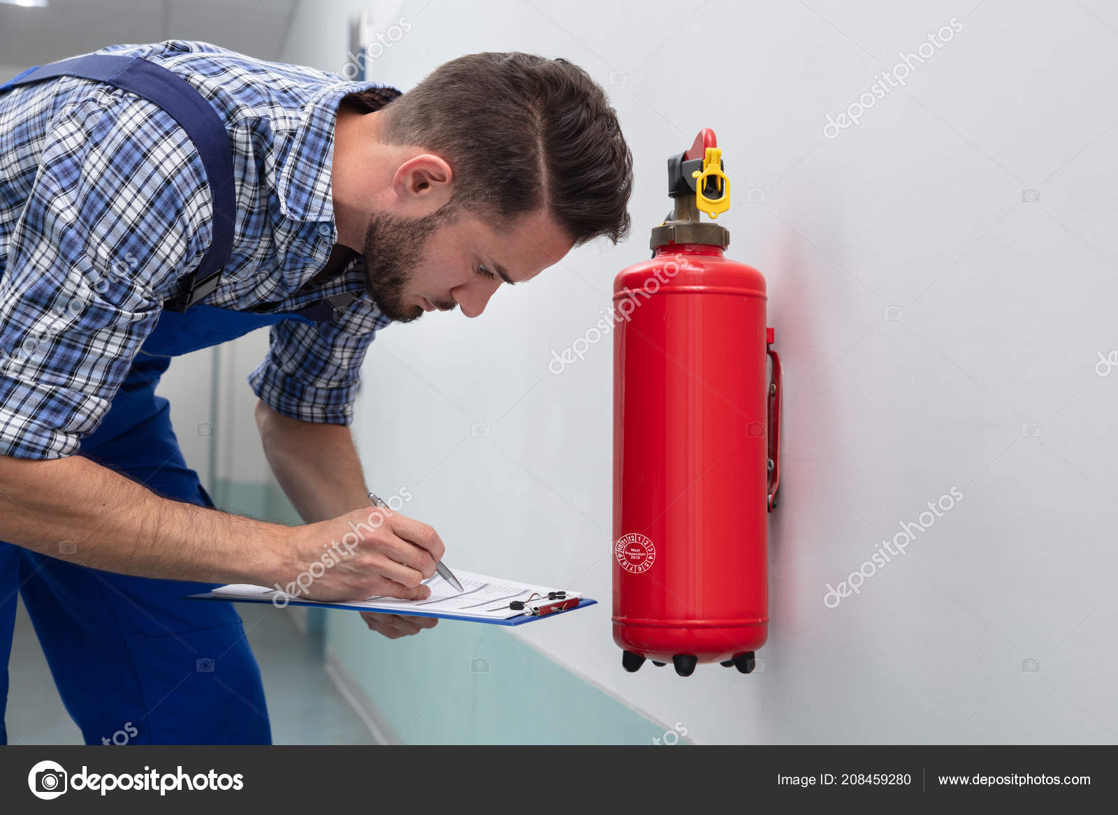 Young Male Technician Checking Symbol Fire Extinguisher Stock Photo by