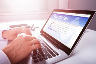 Businessman's Hand Filling Online Registration Form On Laptop clipart