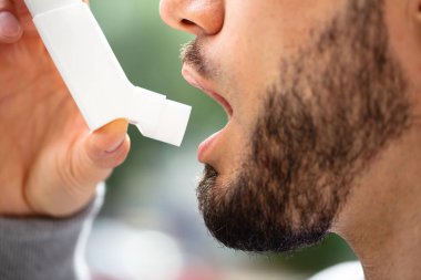 Astım Inhaler saldırıları önlemek için kullanan adam