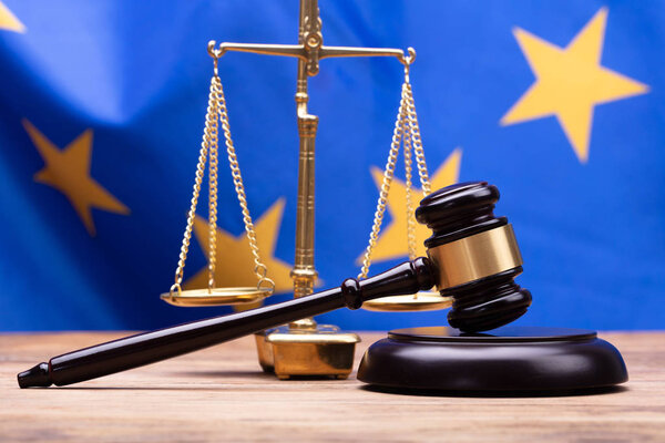 Close-up Of Mallet And Justice Scale In Front Of European Union Flag