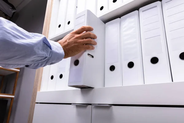 Geschäftsmann Nimmt Büro Ordner Aus Holzregal — Stockfoto