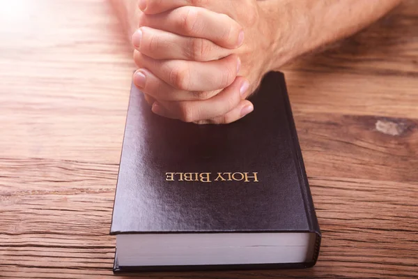 Człowiek Modlitwie Biblią Ręce Nad Podłoże Drewniane — Zdjęcie stockowe