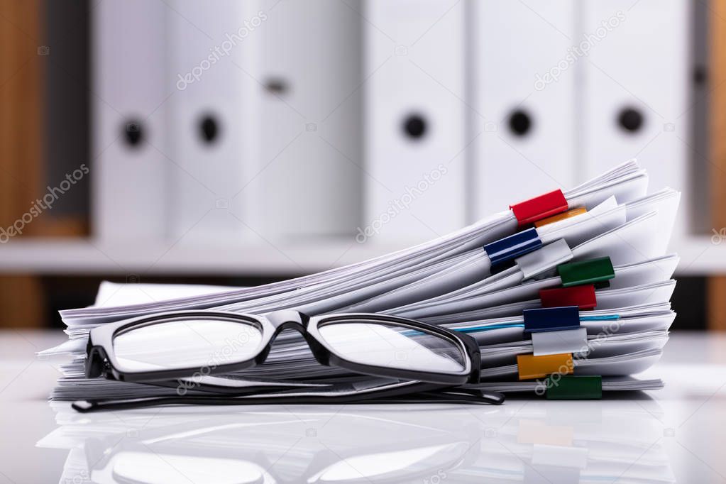 Stacked Documents With Colorful Paperclips And Eyeglasses