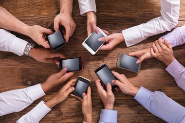 Smartphone üzerinde ahşap arka plan kullanarak iş adamları grubu