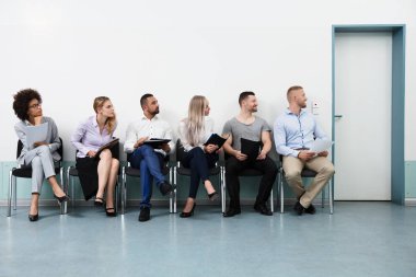 Bir görüşme için bekleyen sandalye üzerinde oturan adaylar