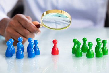 A Male Looking At Colorful Pawns With Magnifying Glass On The Reflective Desk clipart