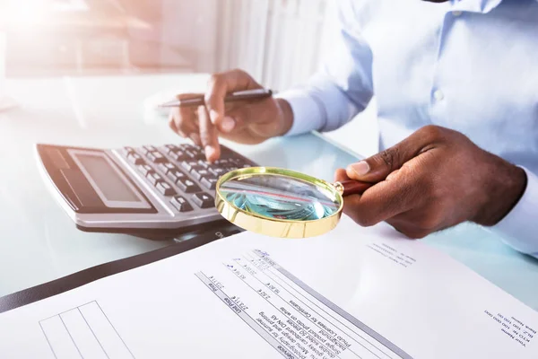 Primer Plano Hombre Negocios Sosteniendo Lupa Sobre Factura Usando Calculadora —  Fotos de Stock