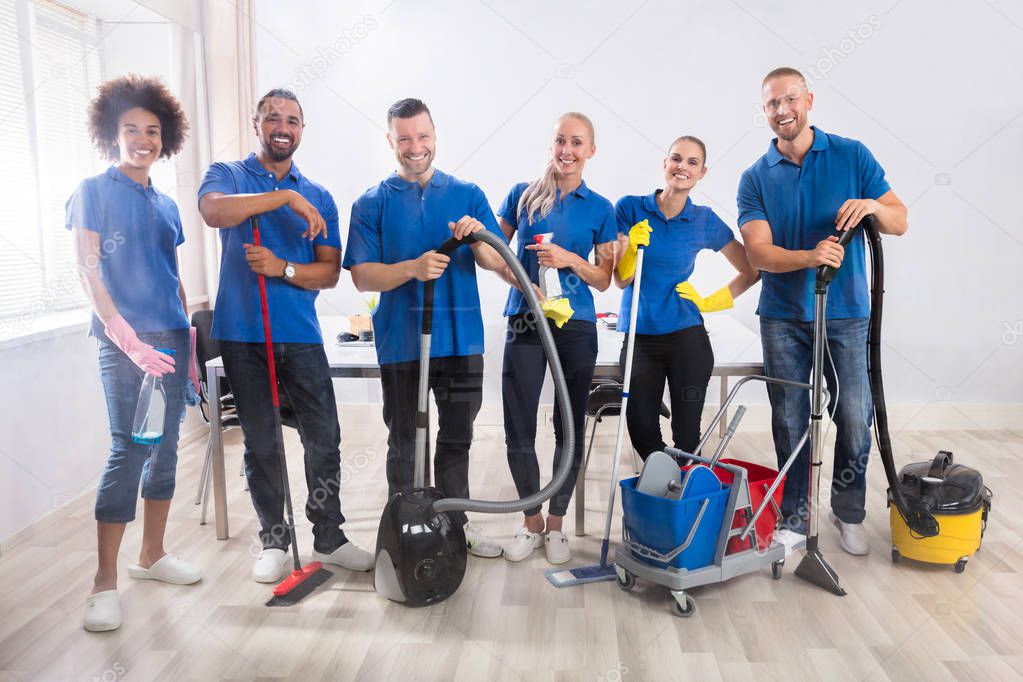 Portrait Of Happy Male And Female Janitors With Cleaning Equipment