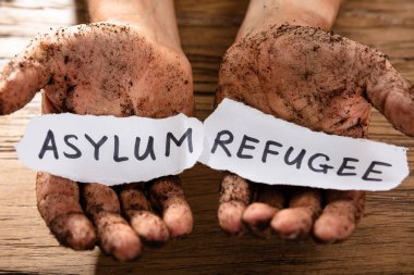 Adamın kirli elleri kağıt gösteren mülteci ve sığınmacı kelimelerin iki adet