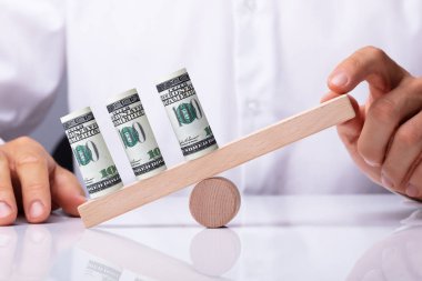 Bir kişinin el Dengeleme Amerikan Doları notlar tahterevalli üzerinde haddelenmiş.