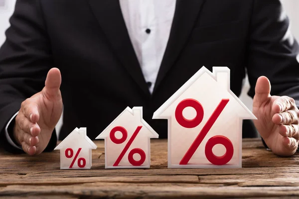Крупный План Руки Предпринимателя Защищающего Растущие Модели Домов Красными Процентами — стоковое фото