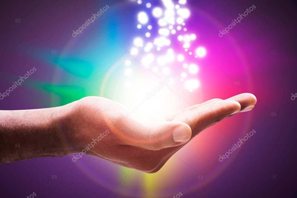 Glowing Lights Flowing From An Open Hand Against Colorful Circle Backdrop