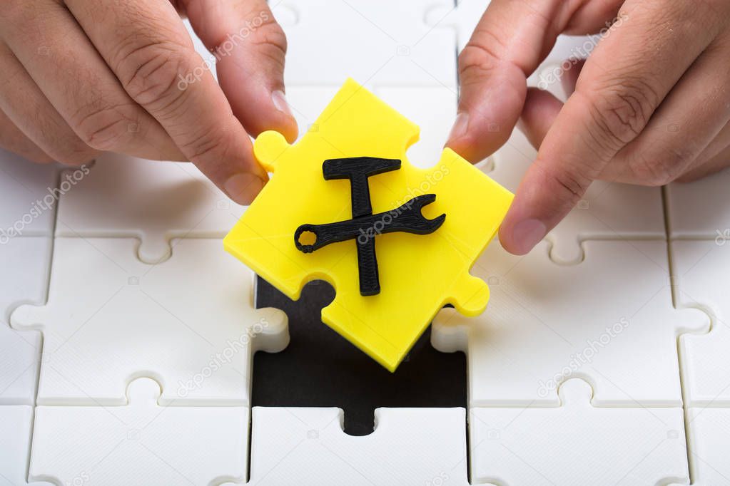 Human hand placing last yellow piece with under construction icon into jigsaw puzzles