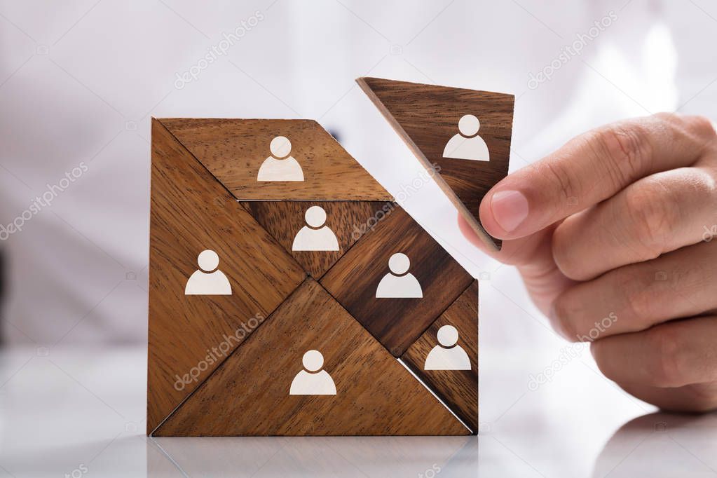 Businessman's hand building tangram square block with human figures