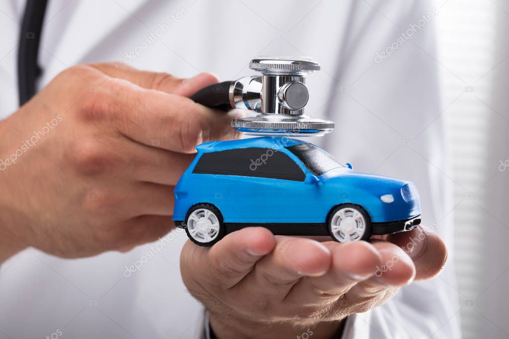 Close-up of a doctor's hand examining blue car