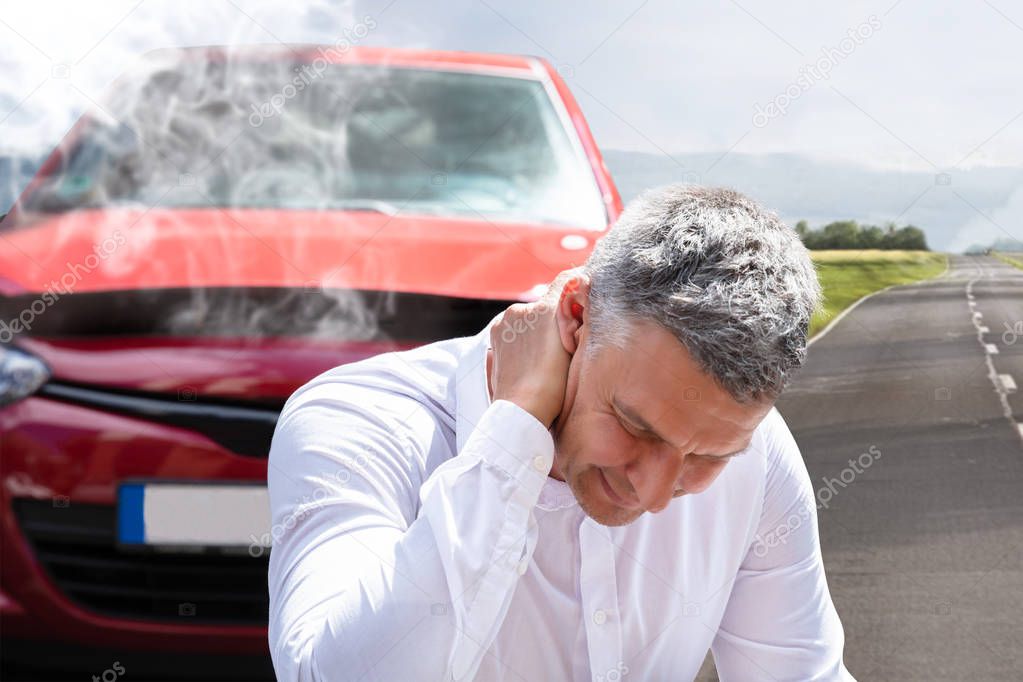 Close-up Of A Mature Man Suffering From Neck Pain In Front Of Breakdown Car