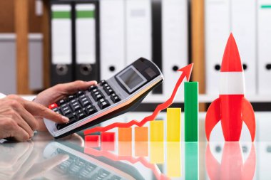 Çok renkli grafik ve roket cam masa yakın hesap makinesini kullanarak işadamı