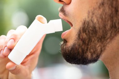 Astım Inhaler saldırıları önlemek için kullanan adam