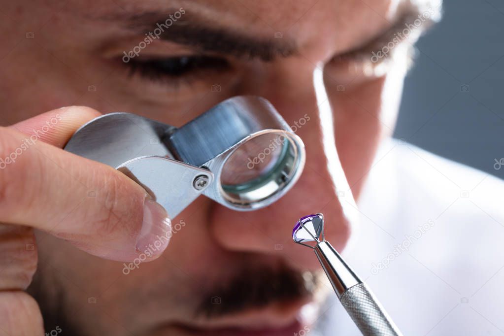 Close-up Of A Male Jeweler's Hand Looking At Diamond Through Magnifying Loupe