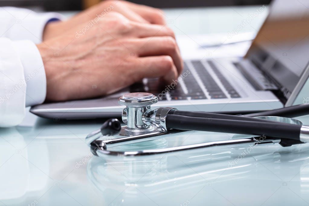 Doctor Using Laptop With Stethoscope On Desk