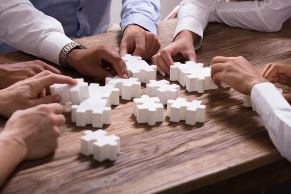 Businesspeople Solving White Jigsaw Puzzle Together Wooden Desk — Stock Photo, Image