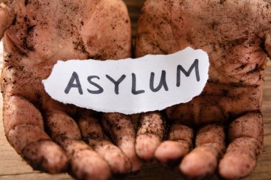 Man's Dirty Hands With Piece Of Paper Showing Asylum Word clipart