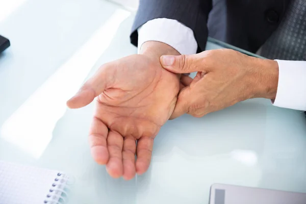 Nahaufnahme Eines Geschäftsmannes Der Schmerzhaftes Handgelenk Über Schreibtisch Hält — Stockfoto