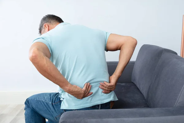 Älterer Mann Sitzt Auf Sofa Und Leidet Unter Rückenschmerzen — Stockfoto