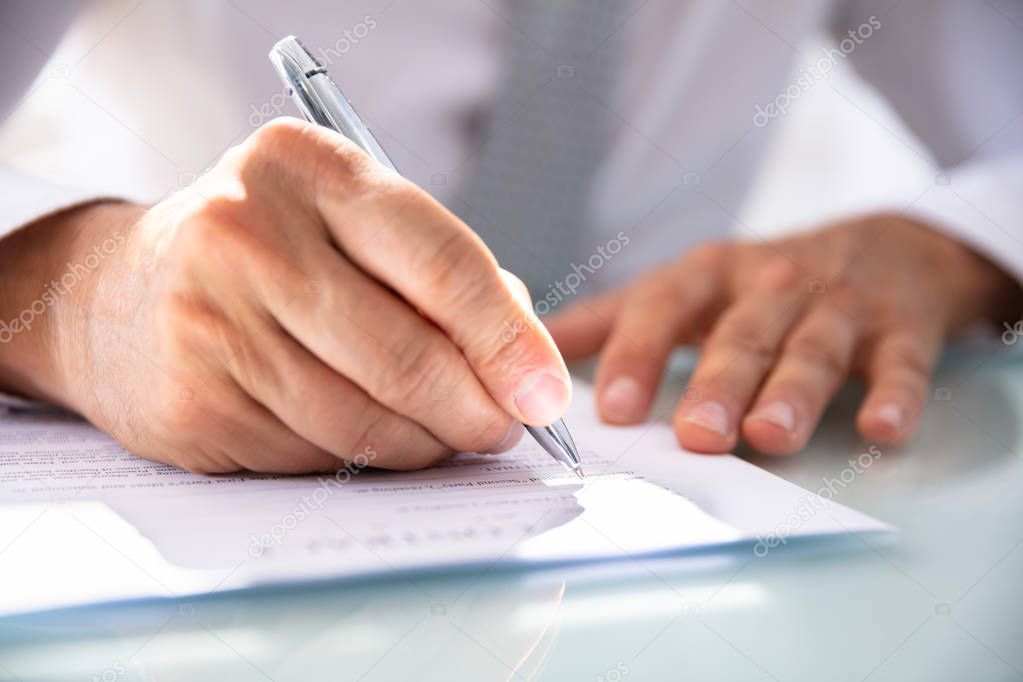 Businessman's Hand Filling Contract Form With Pen