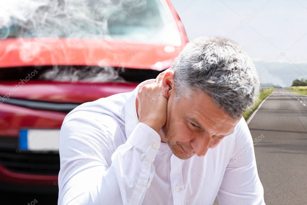 Close-up Of A Mature Man Suffering From Neck Pain In Front Of Breakdown Car