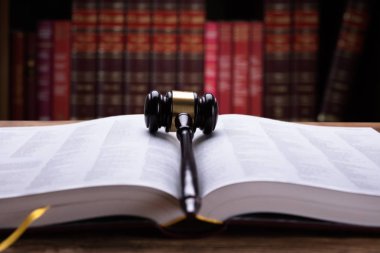 Yakın çekim bir açık kanun kitabı ve mahkeme salonunda tahta tokmak
